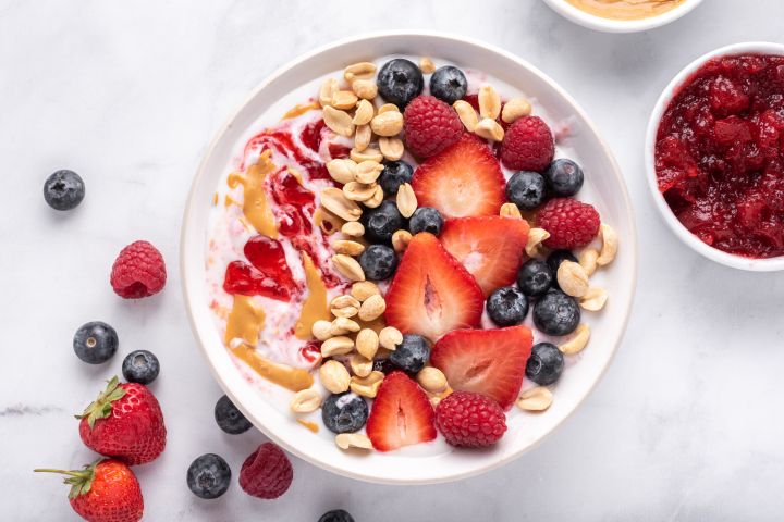 Peanut butter and jelly yogurt bowl with peanut butter, strawberry jelly, peanuts, and fresh fruit.