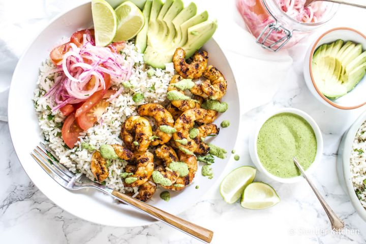 Shrimp rice bowls with grilled shrimp, white rice, cilantro mint sauce, salsa criolla, and sliced avocado.