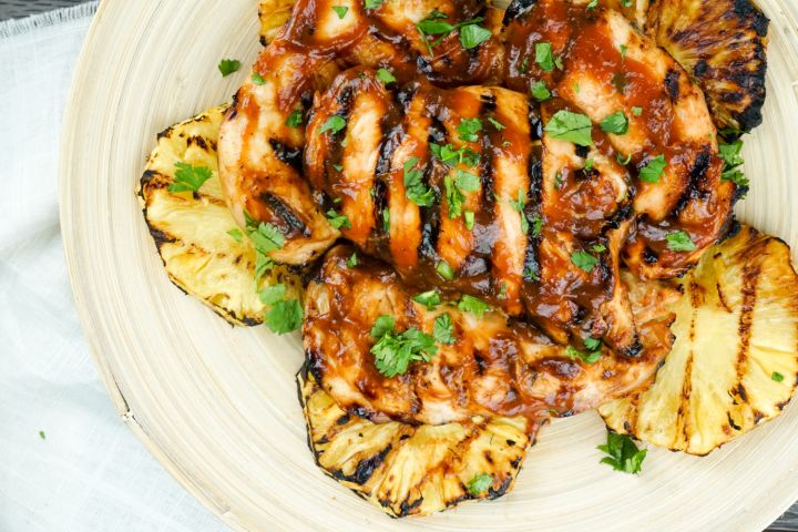 Grilled pineapple chicken with barbecue sauce and grilled pineapple rings.