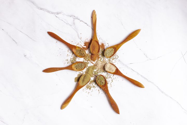 Poultry seasoning on a wooden plate with rosemary, thyme, sage, pepper, garlic, and other spices.