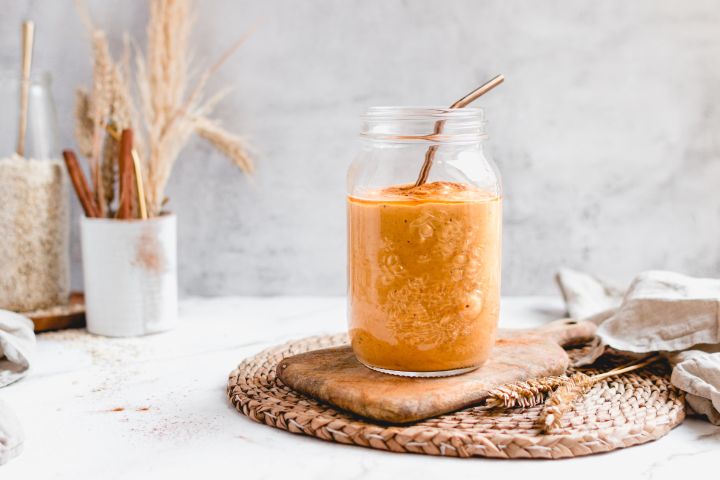 Pumpkin pie smoothie with canned pumpkin, pumpkin spice, almond milk, dates, and oats blended and served in a glass.