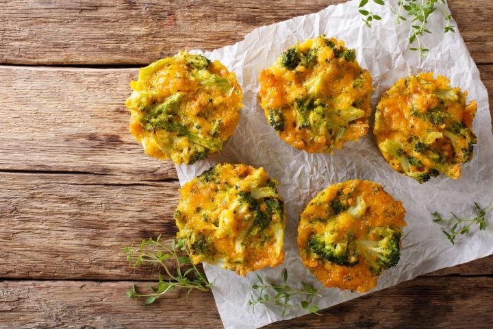 Quiche muffins with broccoli and cheddar cheese on a wooden cutting board.