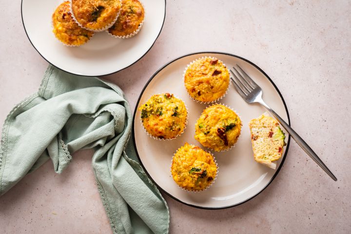 Quinoa egg muffins with cooked quinoa, eggs, broccoli, sundried tomatoes, and shredded cheese served on a plate.
