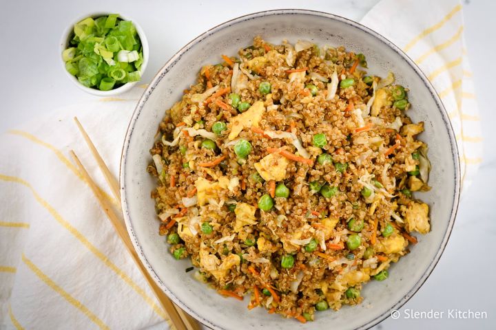 Quinao fried rice with peas, cabbage, eggs, and soy sauce in a bowl with chopsticks.