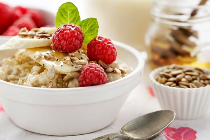 Raspberry overnight oatmeal in a bowl with fresh raspberries and a mint leaf.