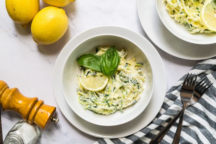 Creamy ricotta zucchini noodles with creamy cheese sauce, lemon, and basil leaves.