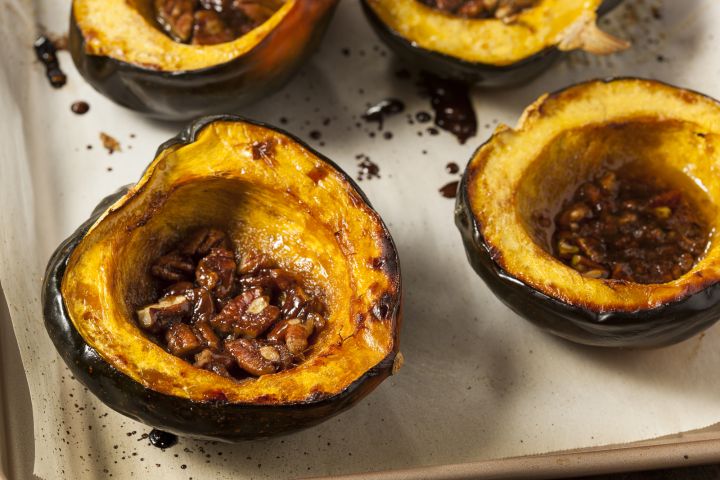 Roasted acorn squash with butter, brown sugar, and cinnamon on a baking sheet.