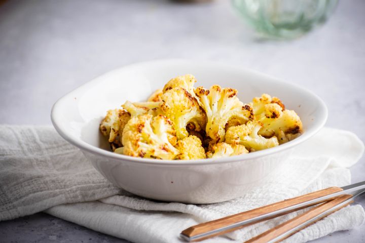 Roasted cauliflower with crispy browned edges in a white bowl.