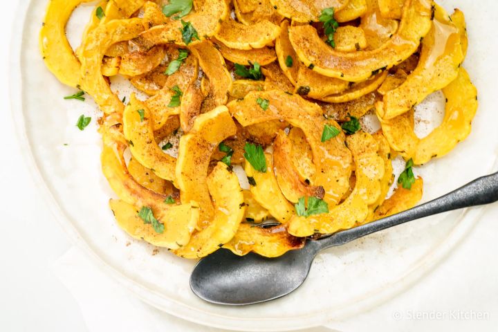 Roasted delicata squash with brown sugar and cinnmon on a white plate.