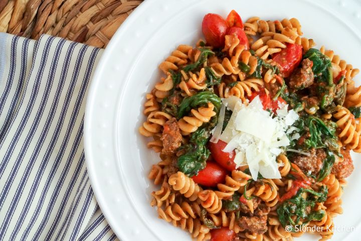 Sausage Arrabbiata pasta with fresh cherry tomatoes and spinach on a plate.