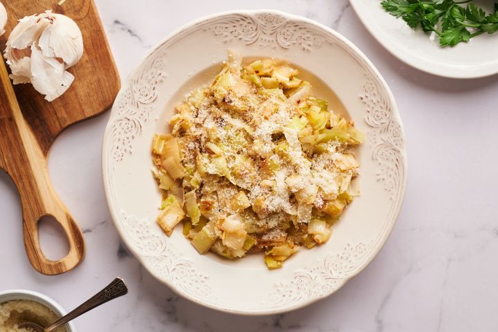 Sauteed leeks in a bowl with garlic, butter, black pepper, and parmesan cheese.