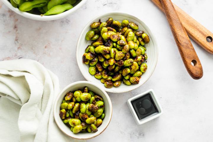 Sauted shelled edamame with caramelized edges served with soy sauce and chili flakes.