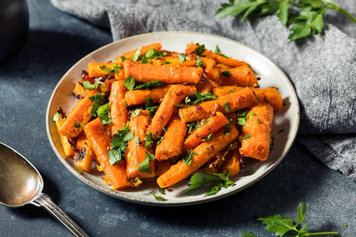 Sesame roasted carrots with soy sauce an sesame oil served on a plate with cilantro.