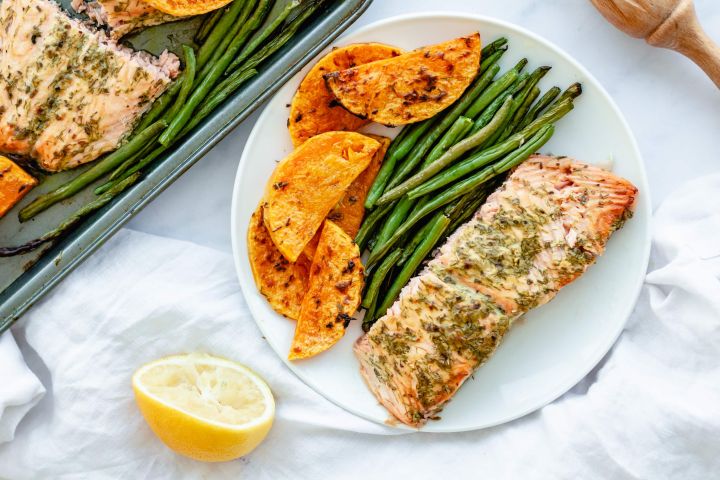 Sheet pan salmon with green beans and butternut squash served with a lemon and mustard sauce on a plate.