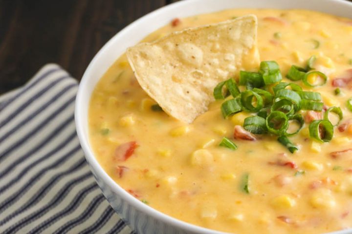 Jalapeno corn dip with cheddar cheese, tomatoes, jalapeno, onion, and corn in a bowl.