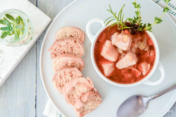 Fish stew with red snapper, carrots, onions, celery root, and herbs in a tomato broth with bread on the side.