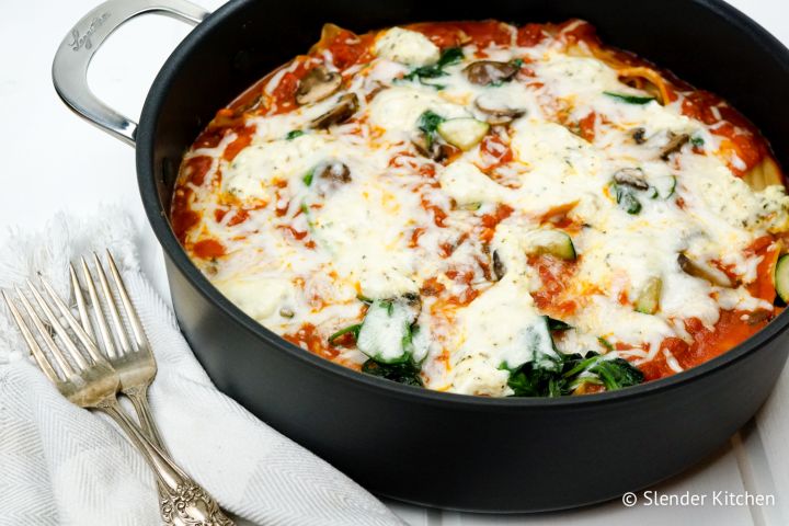 Stovetop lasagna with mushrooms, spinach, melted cheese, and marinara sauce in a skillet.