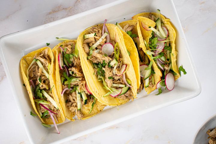 Slow cooker Banh Mi Pork with green onions, cucumbers, radishes, and cilantro in corn tortillas.