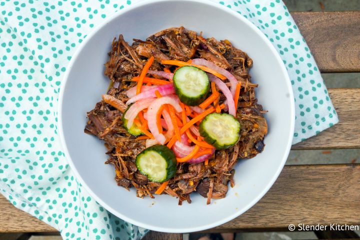 Slow cooker sweet and spicy beef with pickled vegetables on top in a bowl.