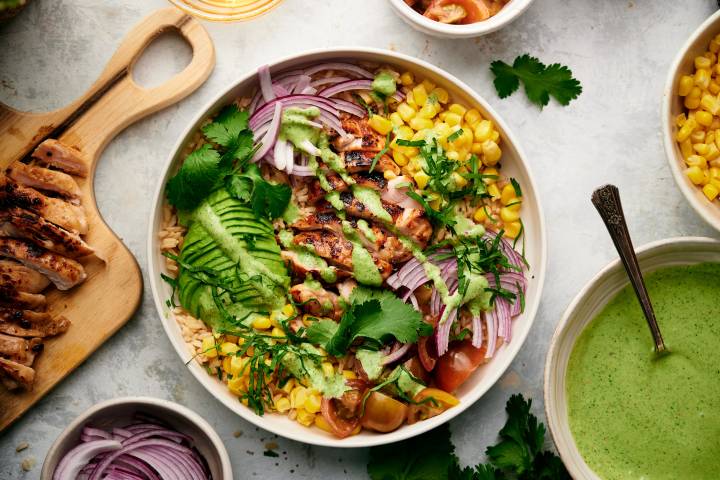 Southwest chicken and rice bowl with grilled chicken, corn, onion, tomatoes, rice, and cilantro yogurt sauce.