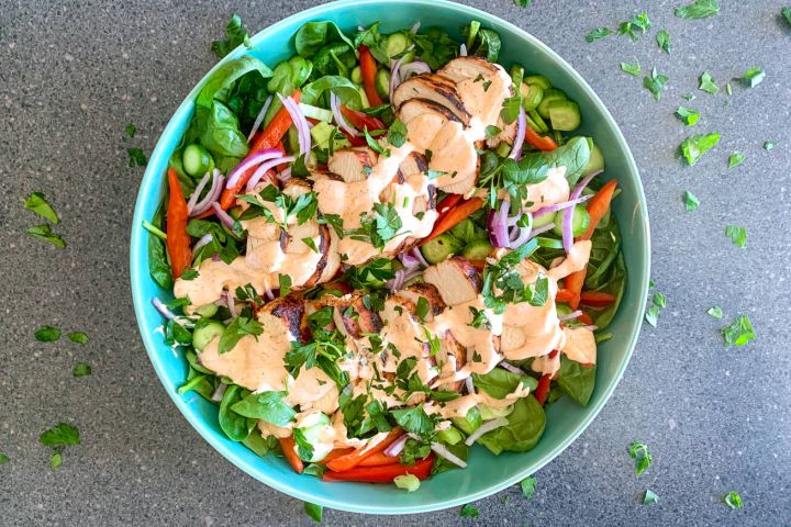 Spicy grilled chicken salad with spinach, red pepper, onions, cucumber, and celery in a yogurt dressing.