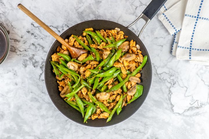 Spicy Ground Turkey stir fry with green beans and mushrooms in a black skillet with a wooden spoon.