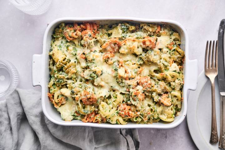 Spinach artichoke pasta with melted cheese in a casserole dish.