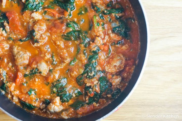 Spinach sausage spaghetti sauce with ground sausage, tomatoes, and spinach in a pot.