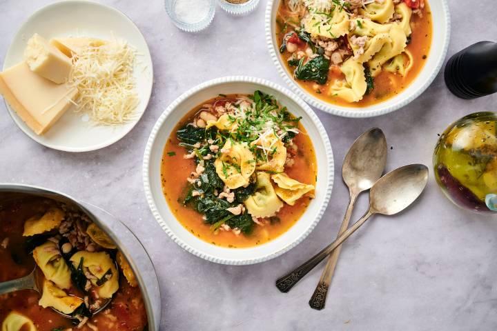 Spinach tortellini soup in a bowl with ground turkey, spinach, white beans, and tomatoes in a white bowl.