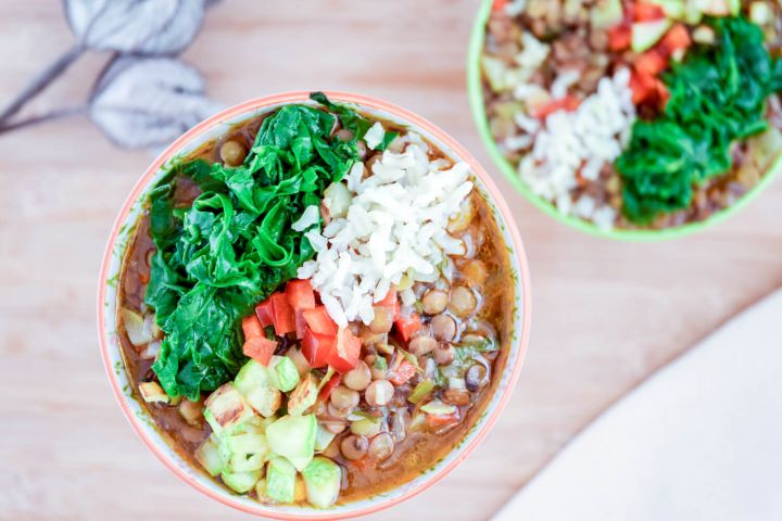 Mexican lentil soup with lentils in a spicy tomato broth served with brown rice, spinach, and zucchini in two bowls.
