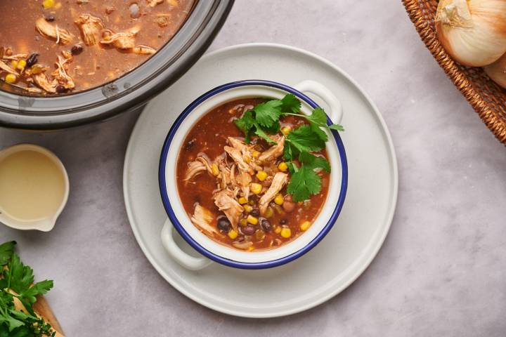 Healthy taco soup with black beans, pinto beans, shredded chicken, cilantro, and cheese.