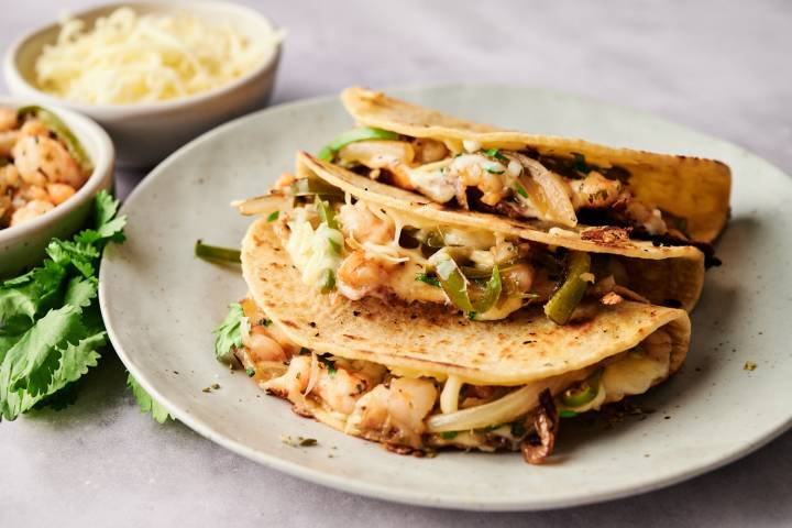 Tacos gobernador with shrimp, melted cheese, poblano peppers, onions, and cilantro in grilled corn tortillas.