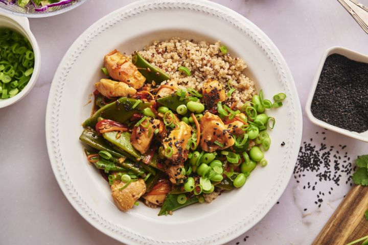 Teriyaki chicken bowls with chicken breast, snow peas, carrots, red pepper, and quinoa in a bowl with teriyaki sauce.