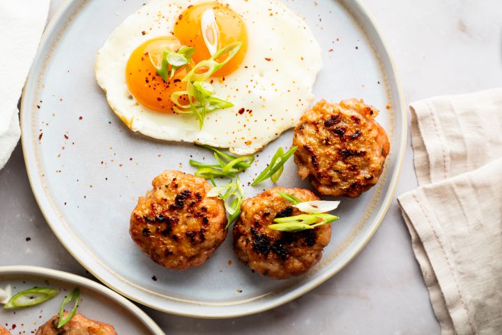 Turkey breakfast sausage served on a plate with sunny side ip eggs and green onions.