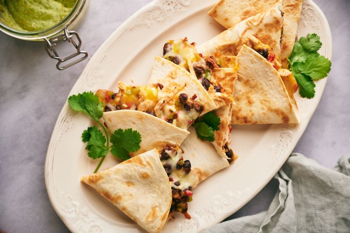 Turkey quesadillas with shredded turkey, black beans, peppers, and cheese cooked in flour tortillas with cilantro and salsa.