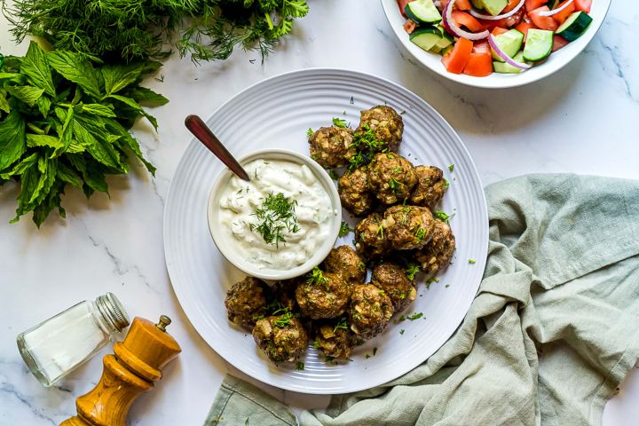 Turkish kofte meatballs made with ground lamb, beef, herbs, and spices served with yogurt sauce and salad.