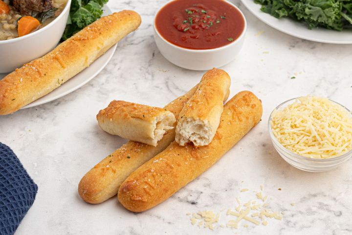 Two ingredient dough breadsticks made with Greek yogurt and self rising flour on a plate with marinara sauce on the side.