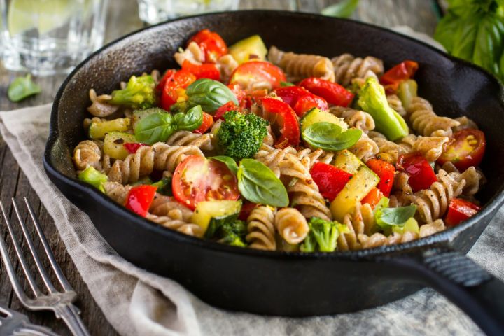 Vegetable scampi in a bowl with broccoli, tomatoes, zucchini, and a garlic butter sauce. 