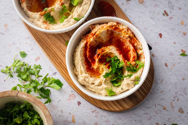White bean hummus served in a bowl with olive oil, paprika, and fresh herbs.