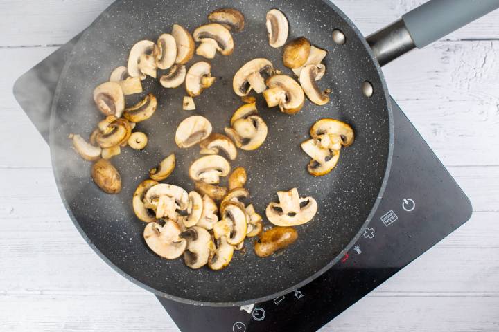 Mushrooms being cooked in a skillet that are golden brown.