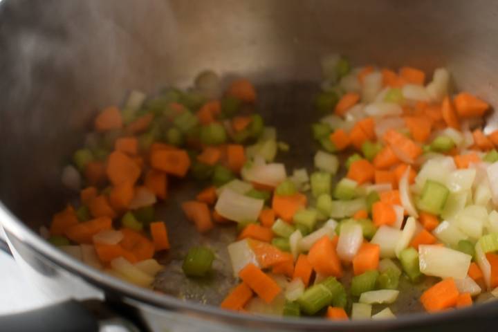 Celery, carrots, and onions cooking in a soup pot.