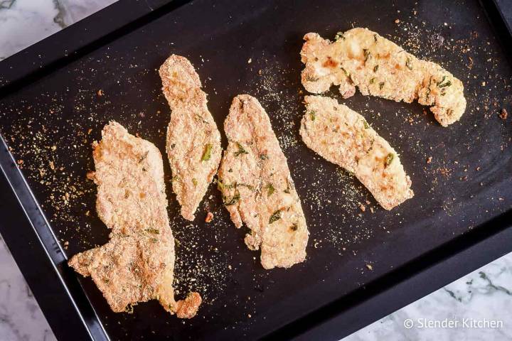 Parmesan chicken on a baking sheet after being taken out of oven.