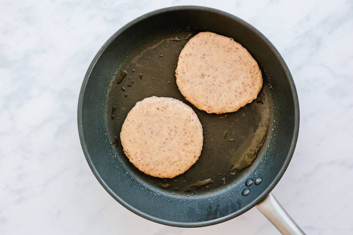 Almond flour pancakes cooking in a skillet.