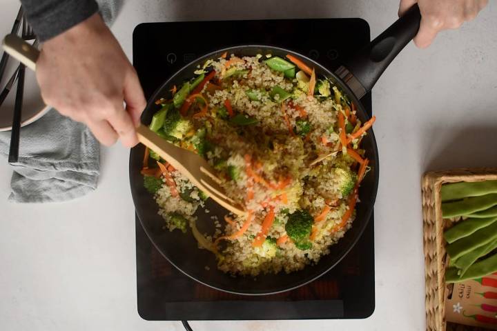 Stir fry sauce being added to a quinoa and vegetable stir fry. 