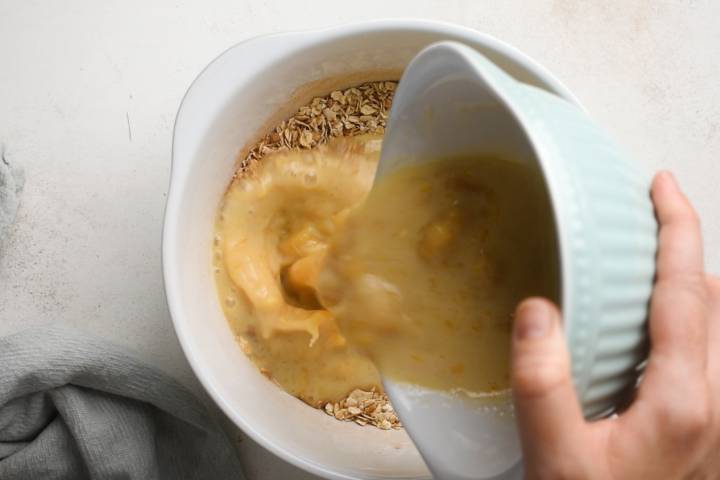 Eggs and banana being stirred in rolled oats in a bowl.