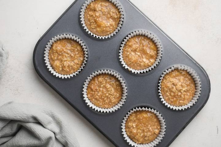 Oatmeal muffins in a muffin tin before being baked.
