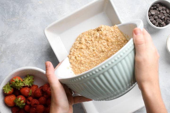 Oatmeal being poured into a baking dish.