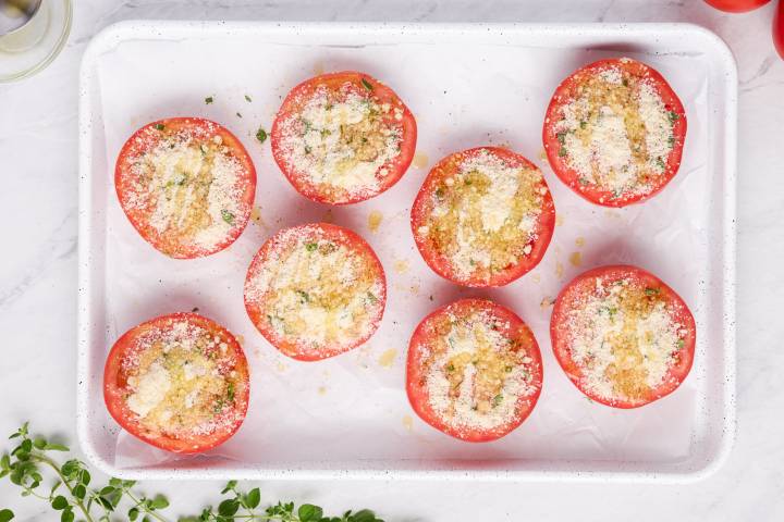 Tomato halves covered with parmesan cheese, herbs, and olive oil.