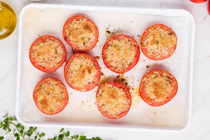Parmesan baked tomatoes with a crispy to on a baking sheet.
