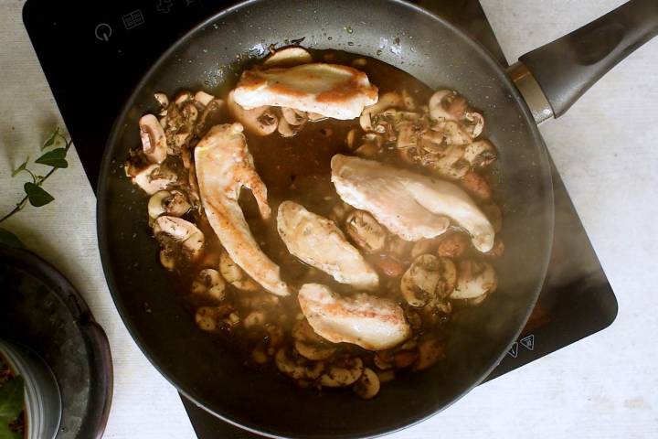 Balsamic chicken and mushrooms simmering in a garlic balsamic sauce in a a pan.